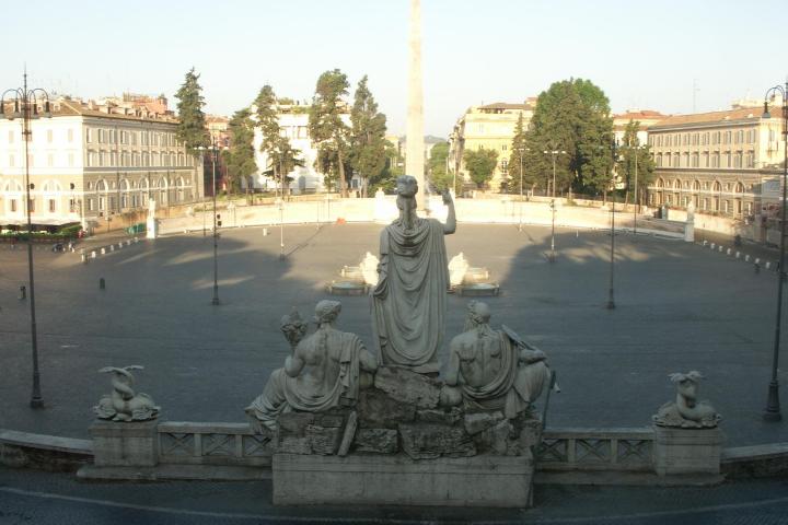 a large ship in a body of water with Piazza del Popolo in the background